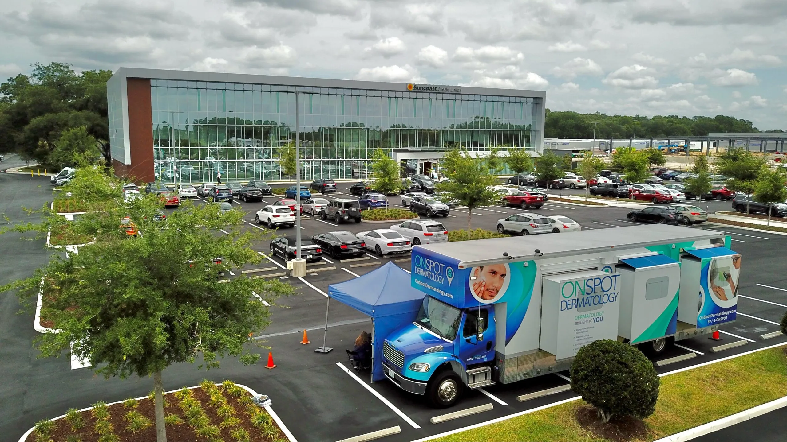 An OnSpot Dermatology mobile clinic vehicle parked outside a Suncoast Credit Union office